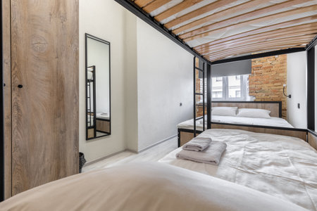 Hostel dormitory room with modern bunk beds and tall mirrorの写真素材