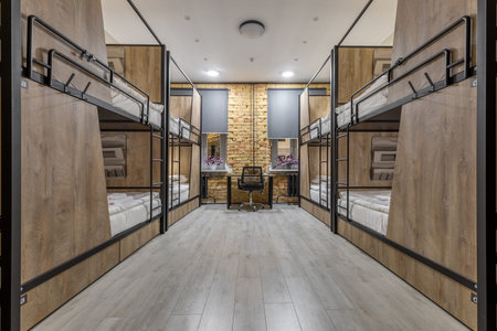 Symmetrical loft hostel dormitory with bunk beds and night city viewの写真素材