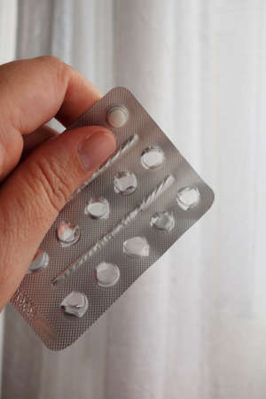 woman's hand holding blisterof medication with one pill left