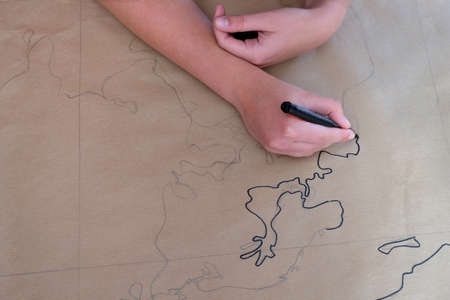 woman's hands drawing a map of the world on brow paper.の写真素材