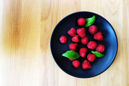 fresh strawberries on black plate and wooden board flat lay.