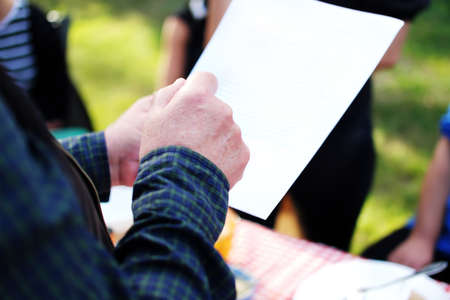 senior man's hand holding a sheet of paper with an anniversary speech, which he makes at his...
