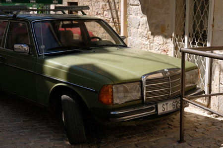 Kastela, Croatia. August 17 2021. Classic green Mercedes Benz 1W123 parked in the narrow street of...