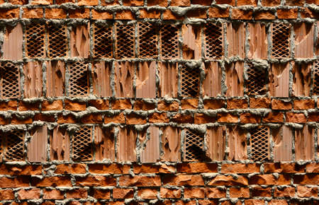 orange perforated cavity brick wall textured backgroundの写真素材