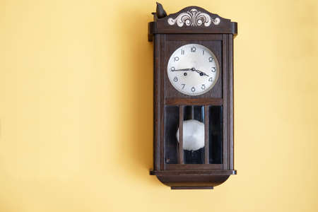 antique wooden grandfather's clock on yellow wall