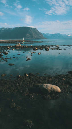 A stony beach with seaweed, aerial photo, view of the lighthouse Hogsteinen on Godoy island, More og...