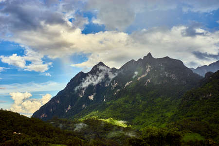 Landscape with rocky mountains seen through the mist and cloudsの写真素材