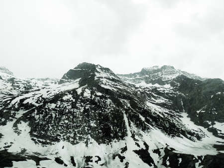 A summer landscape of a mountainous area in foggy weather. Snow-covered valley and mountain peaks covered with snow.の写真素材