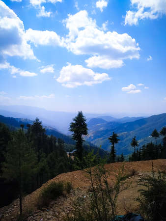 Blue sky with clouds over layers of green hills and mountains. Copy space