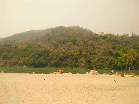 On one side of the river Ganges, the green mountain on the other side sand