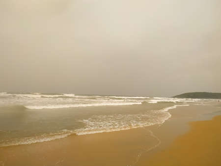 Ocean waves on the beach and white water in Goa, India during the high season. Holidays and travel