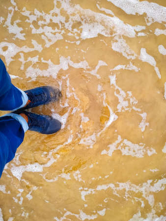 A boy standing in the sea beach wearing shoesの写真素材