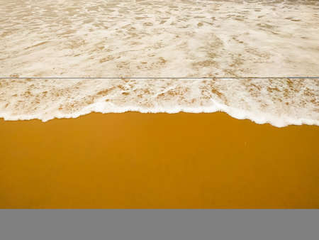 Wave of white bubbles on the sand beachの写真素材