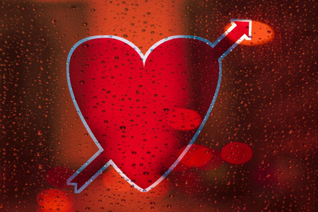 Red heart with arrow on the background of the window with raindrops