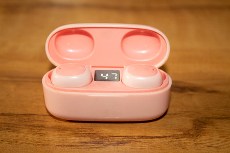 Close up of a pink wireless headphones on a wooden table in the kitchen
