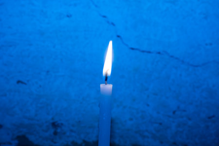 Burning candle on a blue background. Shallow depth of field.