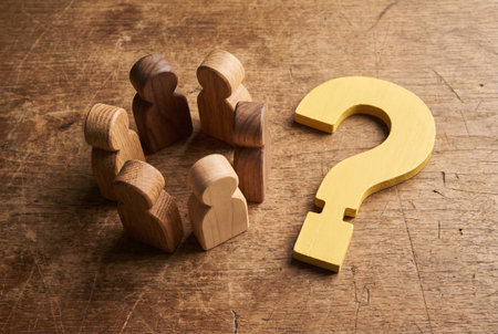 Wooden figures of people with a question mark on a wooden backgroundの素材