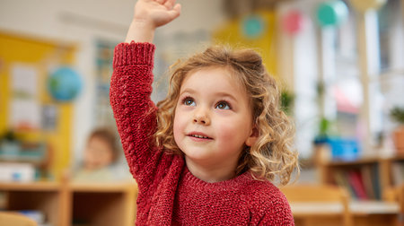 Portrait of cute little girl looking up with raised hand in classroomの素材