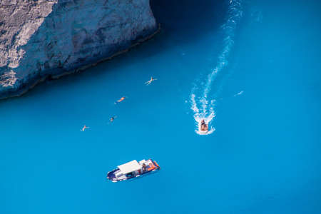People swimming in the blue sea near Navagio Zakynthos, Greece のeditorial素材