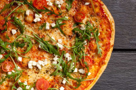 Pizza with cheese, letuce, tomatoes and cheese freshly baked on dark backgroundの写真素材