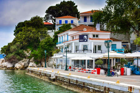 Skiathos town greek tavern by the sea with fishing boat and blue waterのeditorial素材
