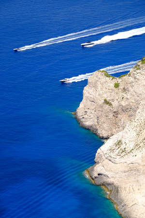 Boats traveling at high speed in clear water near the cliff of Zakynthos Island, Greeceの写真素材
