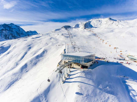 Ski resort in the Alps with ski lift and people skiing on the slope. Aerial viewの写真素材