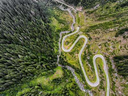 Winding road in the mountains. Forest, tunel and river visible, cars passing by. Transfagarasan road in Trasnylvania, Romania, Europe.の写真素材