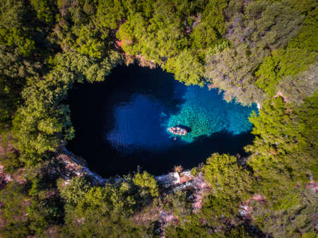 Melissani Cave Kefalonia viewed from above with tourists entering the cave by boatの写真素材