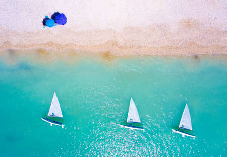 Tourist at the beach with yacht boats and clear blue waters in Lefkada Greeceの写真素材
