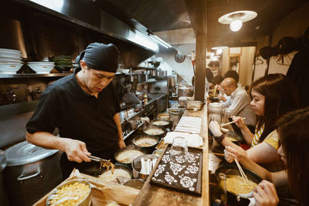 Tokyo, Japan, October 2017: Tourists eating at a traditional street-food restaurant in Tokyo with...