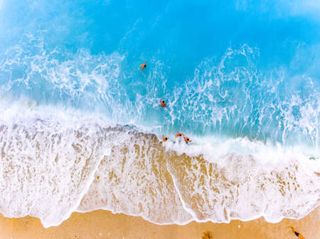 Tourist fighting waves at a beach in Lefkada Greeceの写真素材