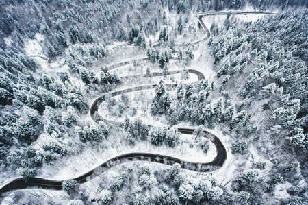 Winter curved winding road in the forest covered in snow