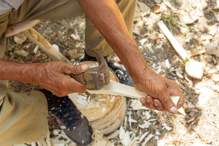 Old man handcrafting a wood sppon the traditional way of making tools in the villages of Romania and Eastern Europeの写真素材