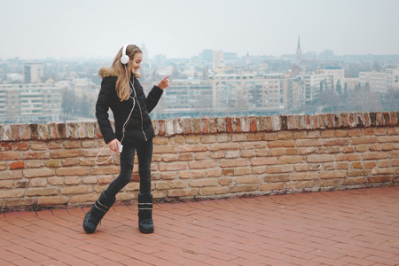 Joyful teenage girl enjoys dancing and listening music using smartphone and headphone smilingの写真素材