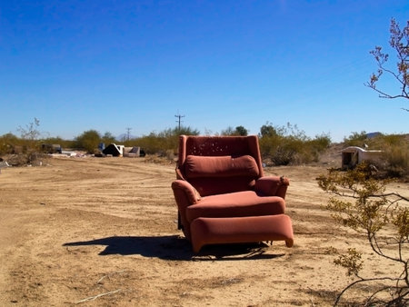 An abandoned reclining chair sitting among other junk in a remote area of Arizona that is used as an illegal trash dump.の写真素材
