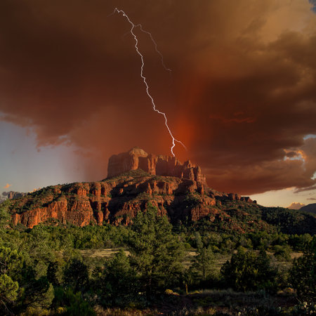 HDR composite of a storm cell rolling over Cathedral Rock in Sedona Arizona near sundown. Composed of 3 exposures. One for the landscape. One for the storm, and one for the lightning.の写真素材