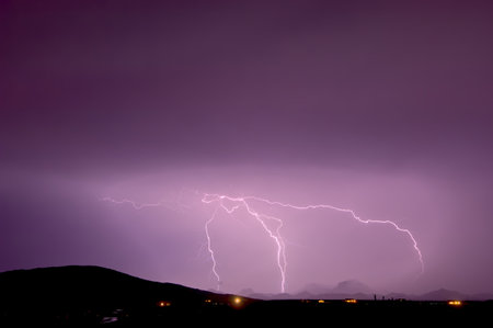 Lightning striking the Gila Bend Mountains in Arizona during a 2011 Monsoon storm. The pink color...