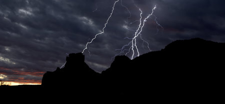 Lightning striking behind Castle Rock in Sedona AZ at sundown.