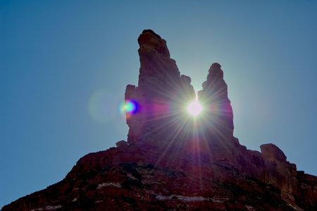 The sun setting behind a rock formation in Valley of the Gods known as the King and Queen.の写真素材