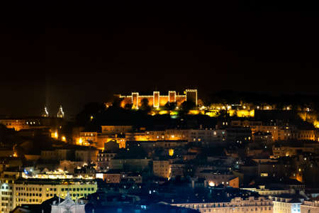 Saint George Moorish castle occupying a hilltop overlooking the center of Lisbon and Tagus River. Night illuminations during Christmas holiday seasonの写真素材
