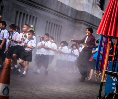 BANGKOK, THAILAND - FEBRUARY 13 School children during Buddhist holidays carrying lotus flowers around the temple, raising up the dust- Wat Traimitr Withayaram on February 13,2014 Bangkok,Thailand のeditorial素材
