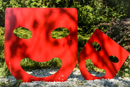 Big and small red metal  theatrical mask in park のeditorial素材