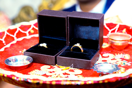 box with a gold wedding ring with a diamond is in the petals of red rosesの写真素材