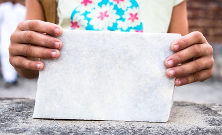 Girl holds in his hand an empty stone plate for the text.