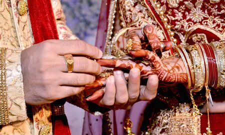 Close up on hand of a man put on an engagement ring on the finger of the brideの写真素材