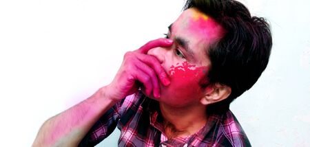 Closeup shot of Indian young man covered with multi color dry paint at Holi Festival.