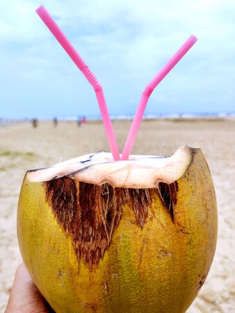Male hand with a coconut on the beach