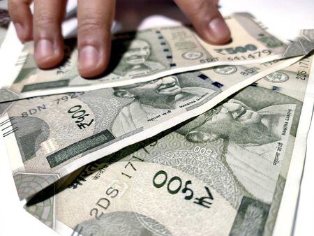 Hand holding five hundred Indian rupee notes against white backgroundの写真素材
