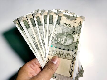 Hand holding five hundred Indian rupee notes against white backgroundの写真素材